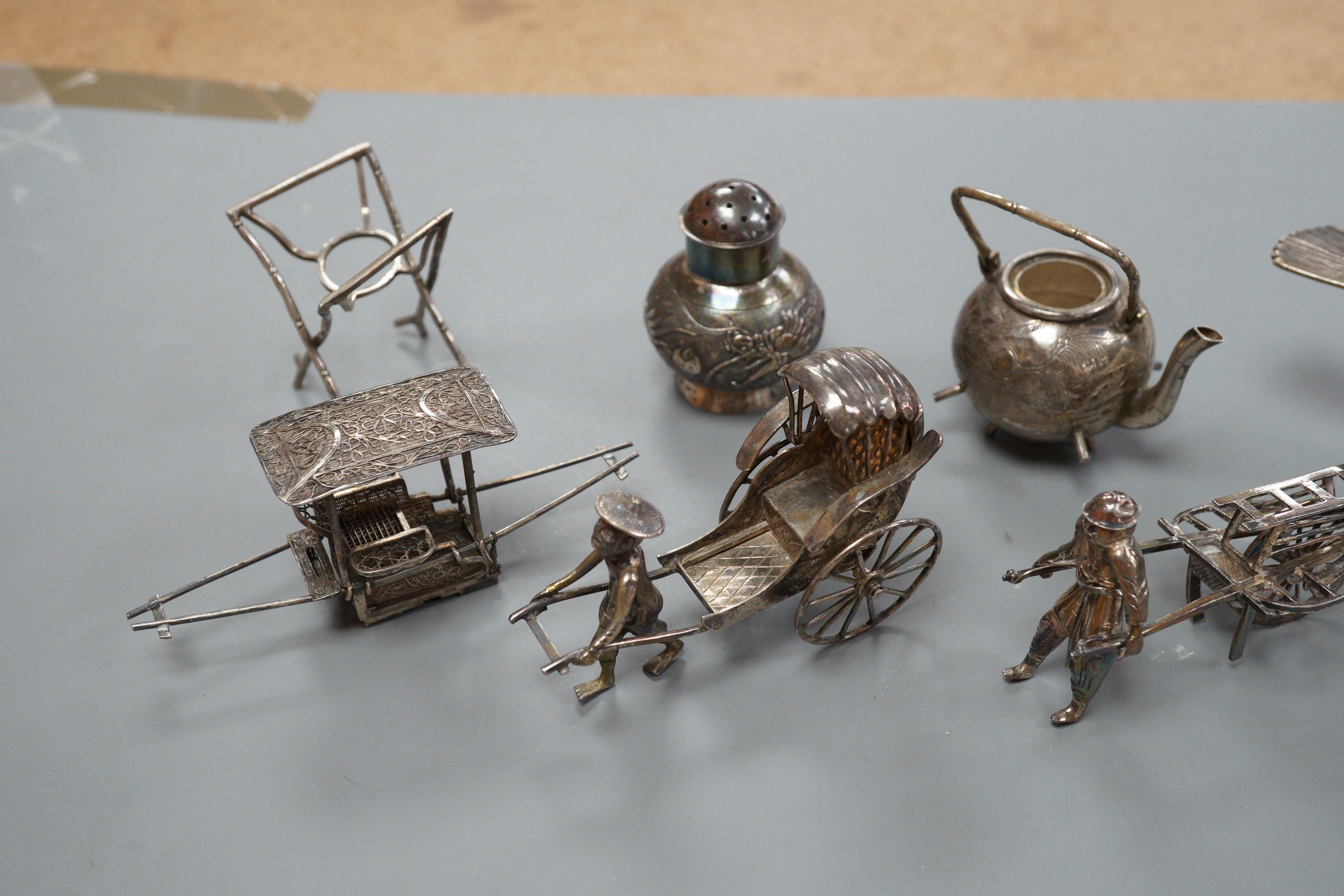 Six assorted miniature white metal items including a Chinese tea kettle on stand (lacking lid), height 93mm, maker CS, a similar rickshaw with driver, maker CH, a Chinese condiment and three other items.